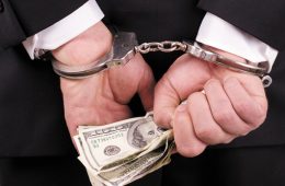 arrested businessman holding hundred dollar bills isolated on a white background